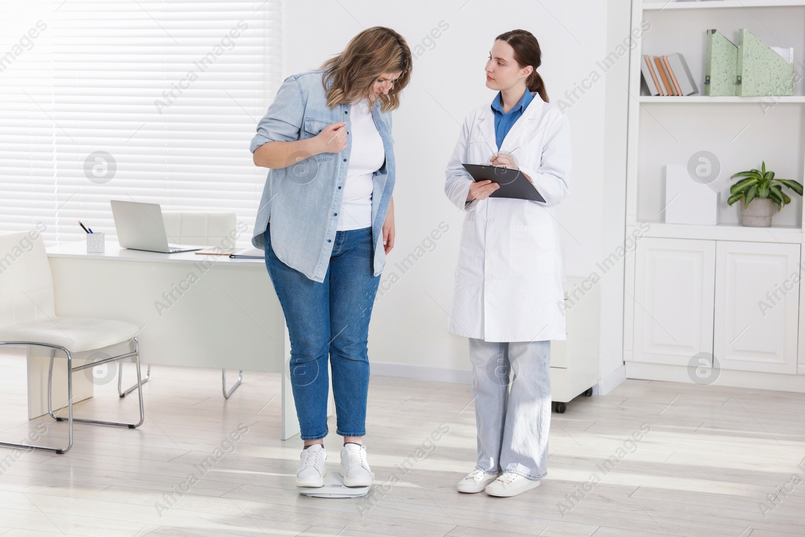 Weight loss. Overweight woman standing on scales during consultation with nutritionist in clinic Photo of Weight loss. Overweight woman standing on scales during consultation with nutritionist in clinic