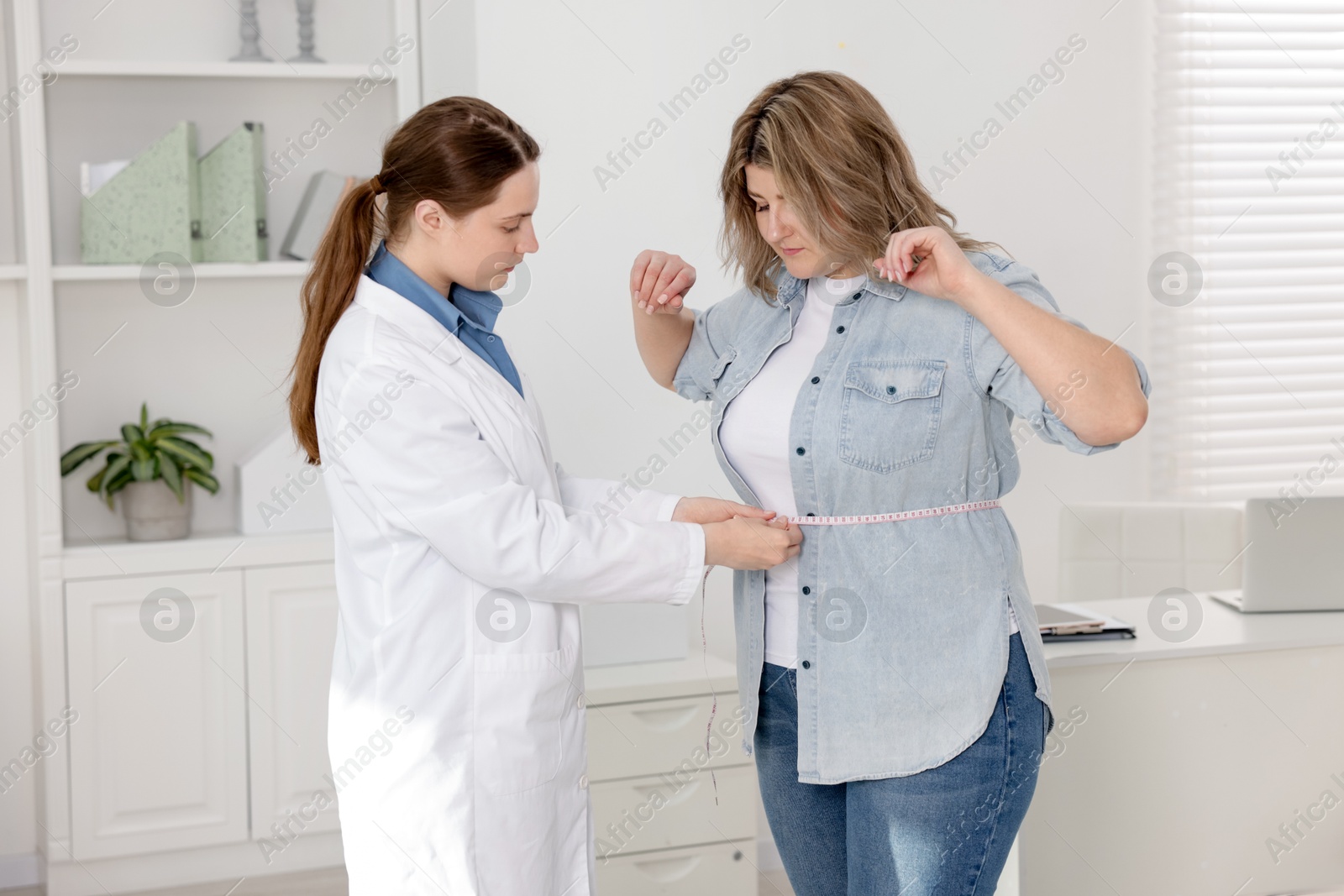 Photo of Weight loss. Nutritionist measuring overweight woman's waist with tape in clinic