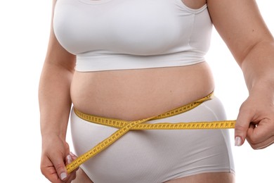 Photo of Weight loss. Plus size woman measuring waist with tape on white background, closeup