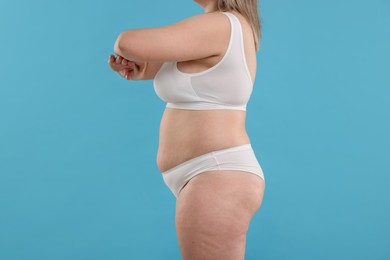 Photo of Weight loss. Plus size woman in underwear on light blue background, closeup
