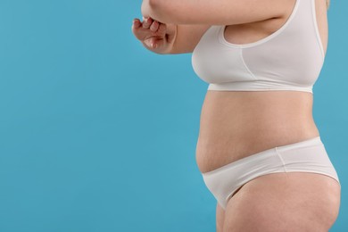 Photo of Weight loss. Plus size woman in underwear on light blue background, closeup