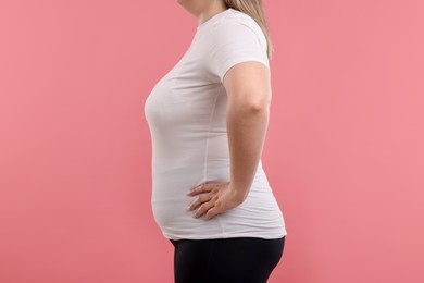 Photo of Weight loss. Plus size woman on pink background, closeup