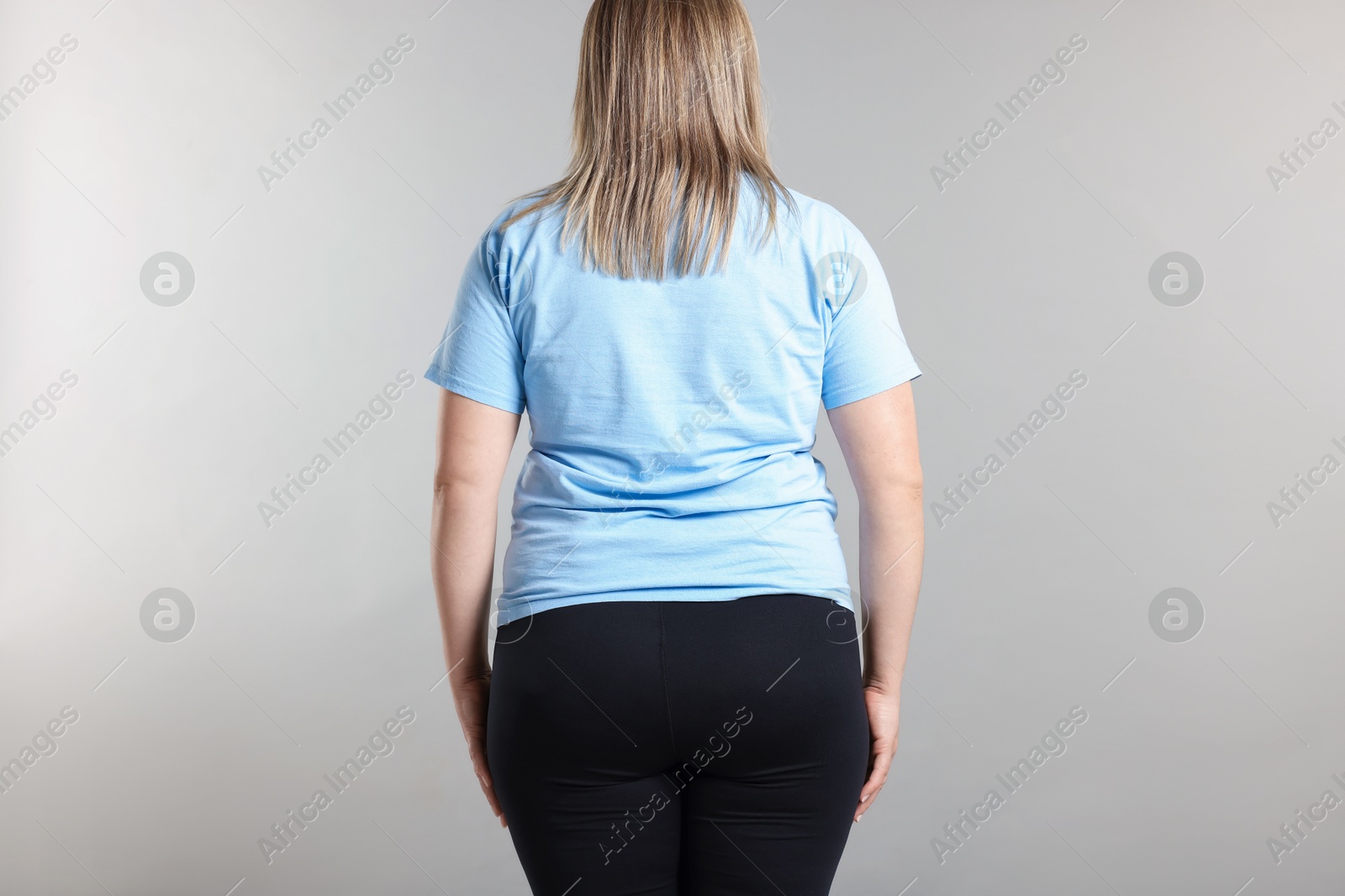 Weight loss. Plus size woman on gray background, back view Photo of Weight loss. Plus size woman on gray background, back view