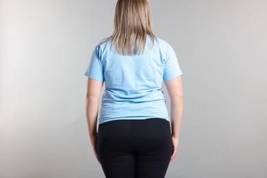 Photo of Weight loss. Plus size woman on gray background, back view