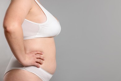 Photo of Weight loss. Plus size woman in underwear on gray background, closeup. Space for text