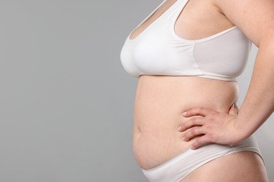 Photo of Weight loss. Plus size woman in underwear on gray background, closeup. Space for text