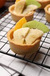 Photo of Tartlets with fruits and mint on table, closeup. Delicious dessert