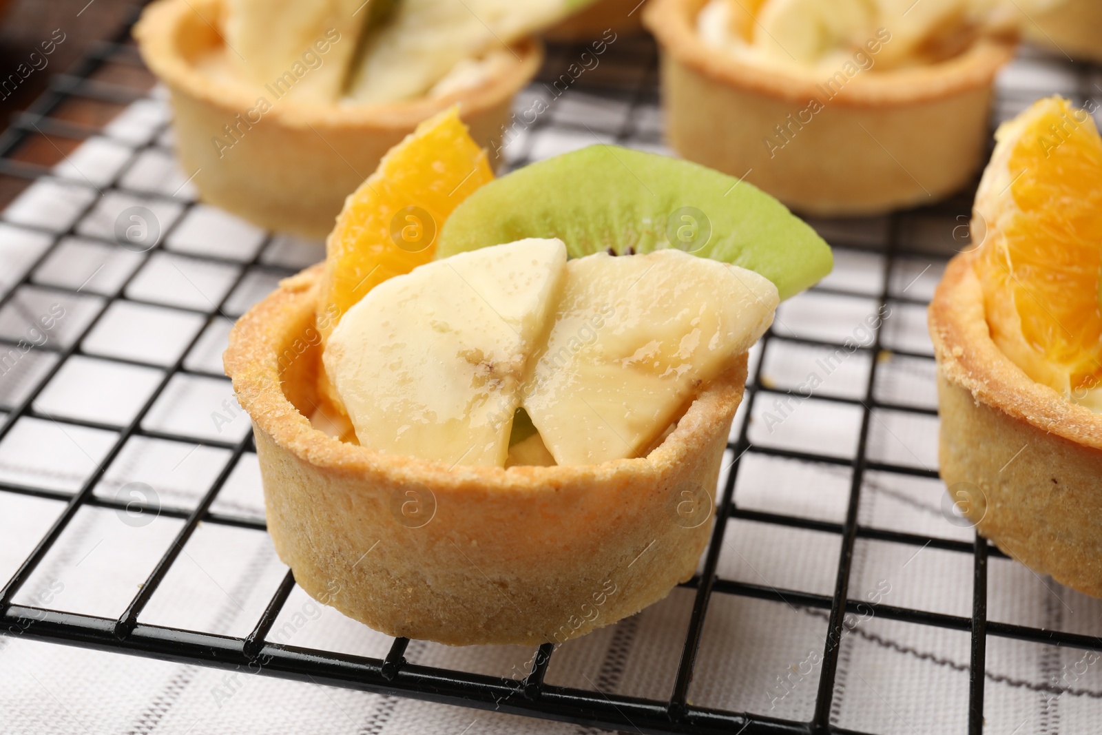 Tartlets with fruits and mint on table, closeup. Delicious dessert Photo of Tartlets with fruits and mint on table, closeup. Delicious dessert