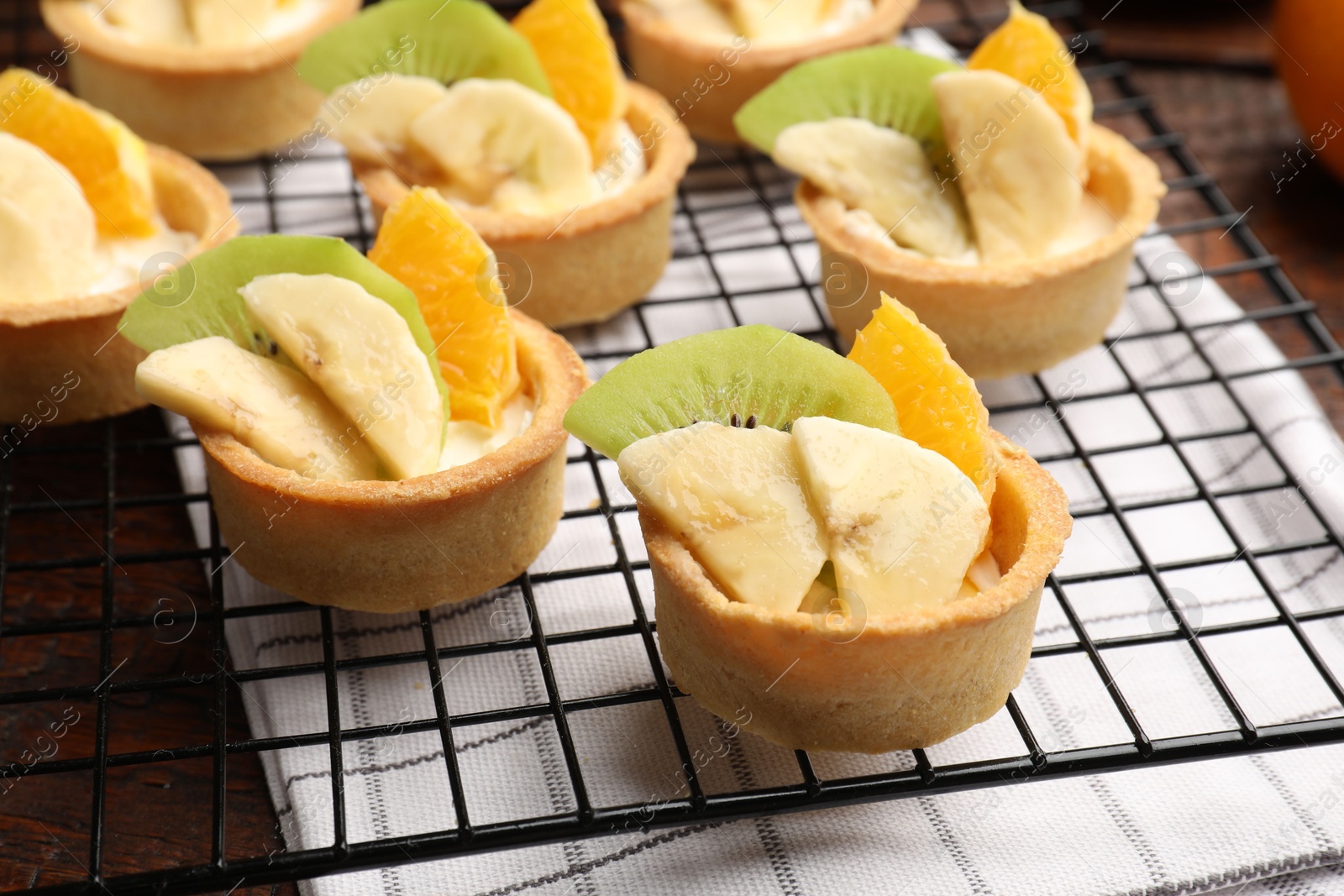 Tartlets with fruits and mint on table, closeup. Delicious dessert Photo of Tartlets with fruits and mint on table, closeup. Delicious dessert