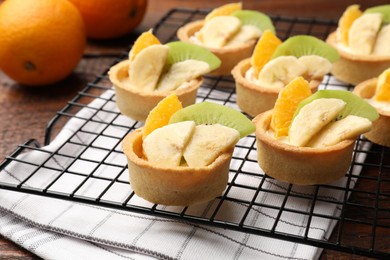 Photo of Tartlets with fruits and mint on table, closeup. Delicious dessert