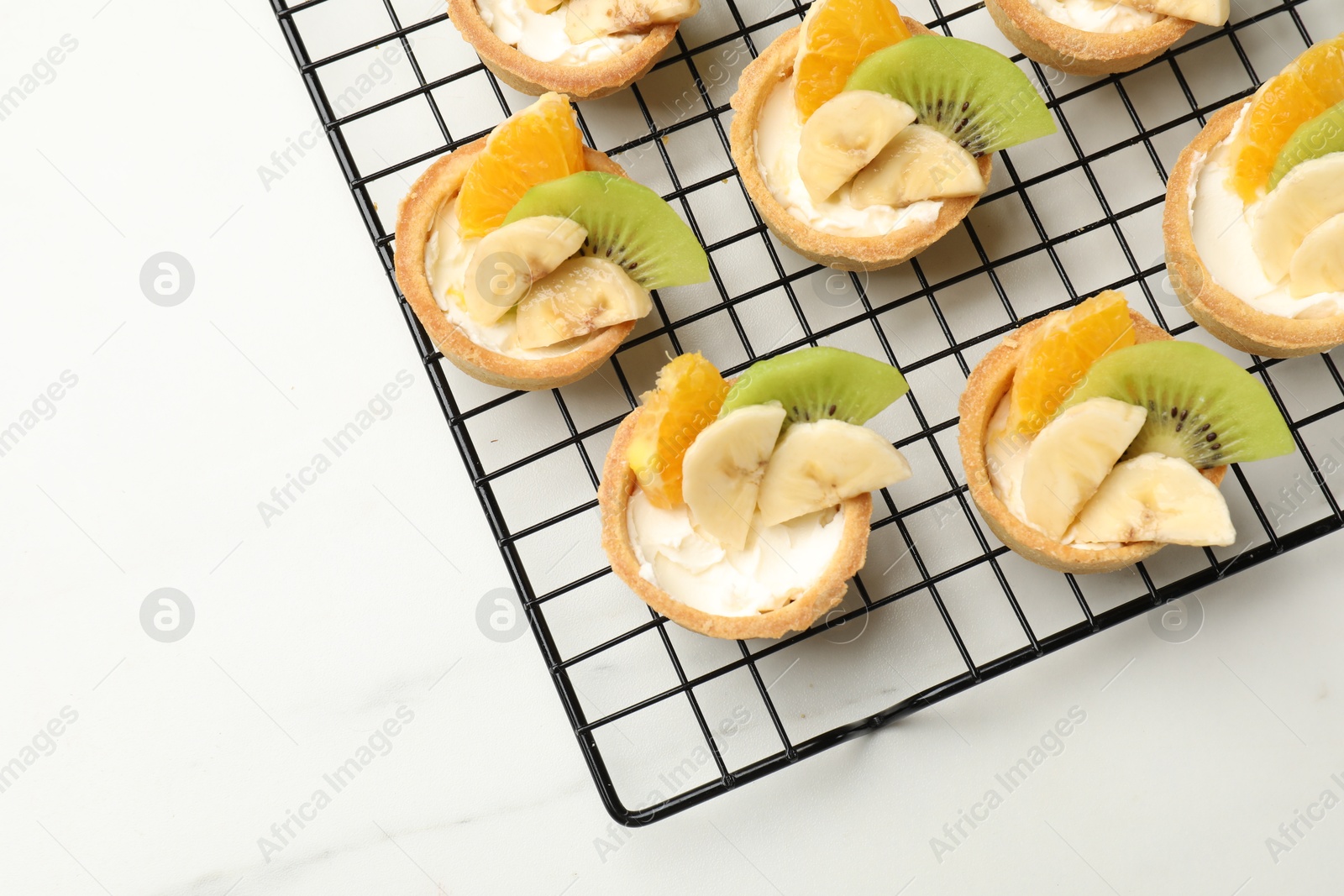 Tartlets with fruits on white marble table, top view. Delicious dessert Photo of Tartlets with fruits on white marble table, top view. Delicious dessert