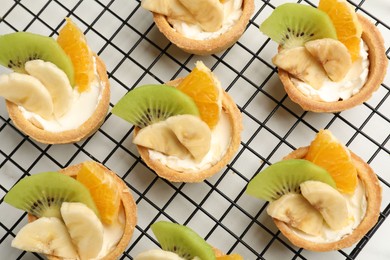 Photo of Tartlets with fruits on white table, top view. Delicious dessert