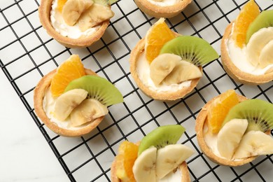 Photo of Tartlets with fruits on white table, top view. Delicious dessert