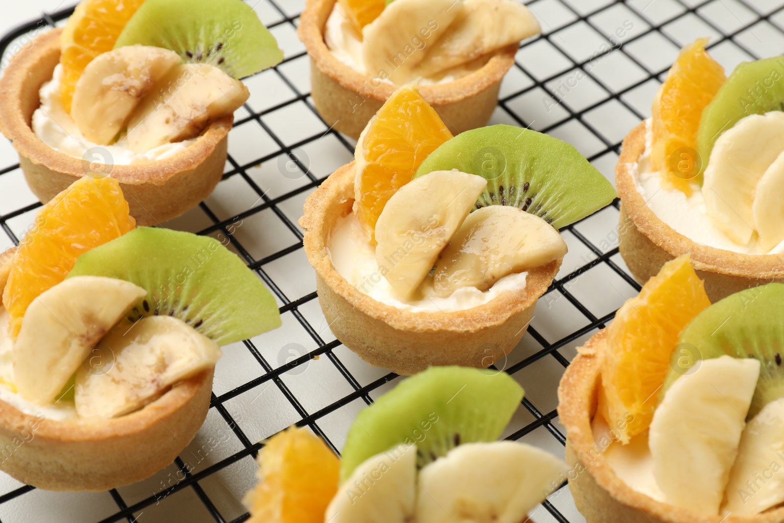 Tartlets with fruits on table, closeup. Delicious dessert Photo of Tartlets with fruits on table, closeup. Delicious dessert