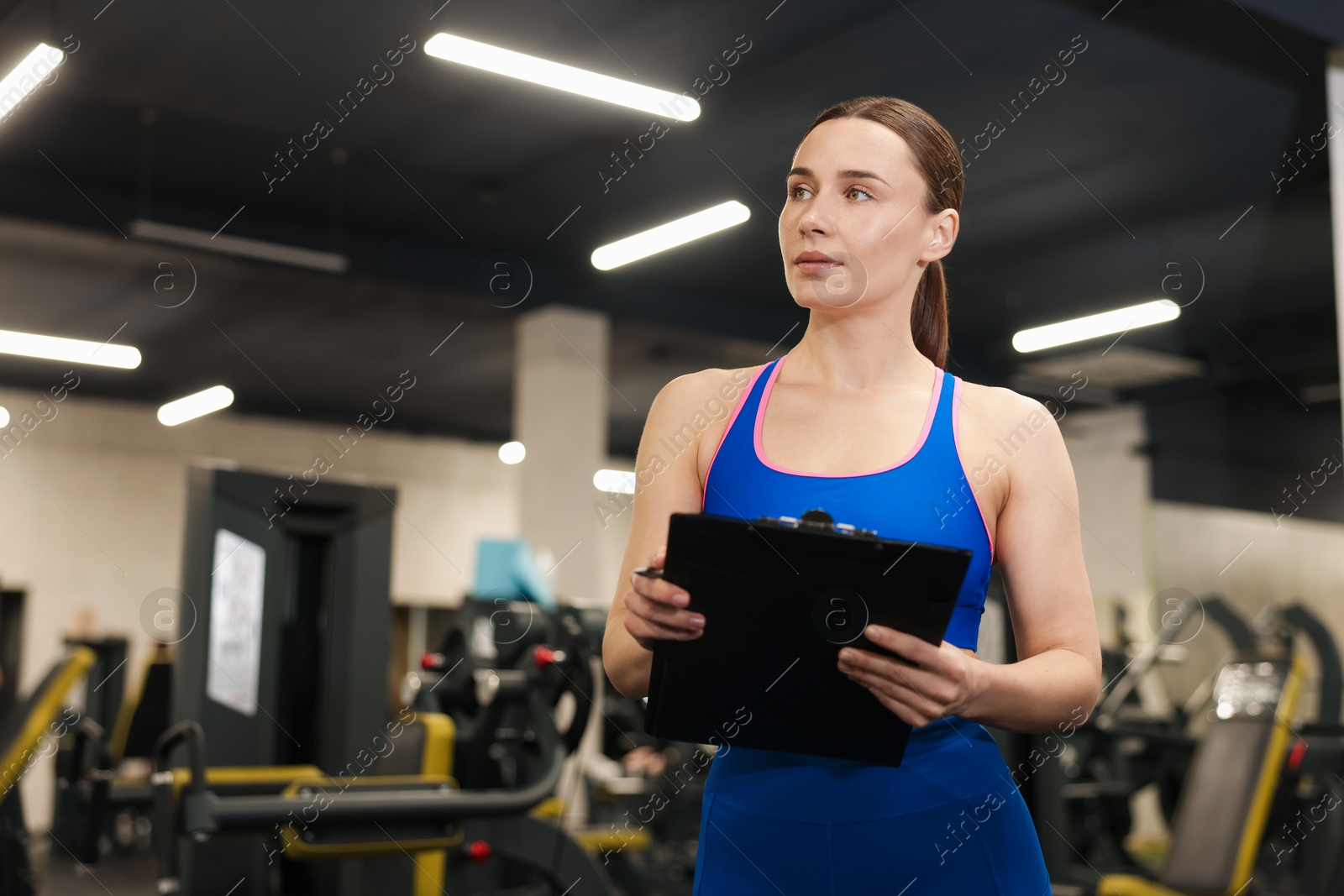 Professional personal trainer with clipboard in gym. Space for text Photo of Professional personal trainer with clipboard in gym. Space for text
