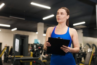 Photo of Professional personal trainer with clipboard in gym. Space for text