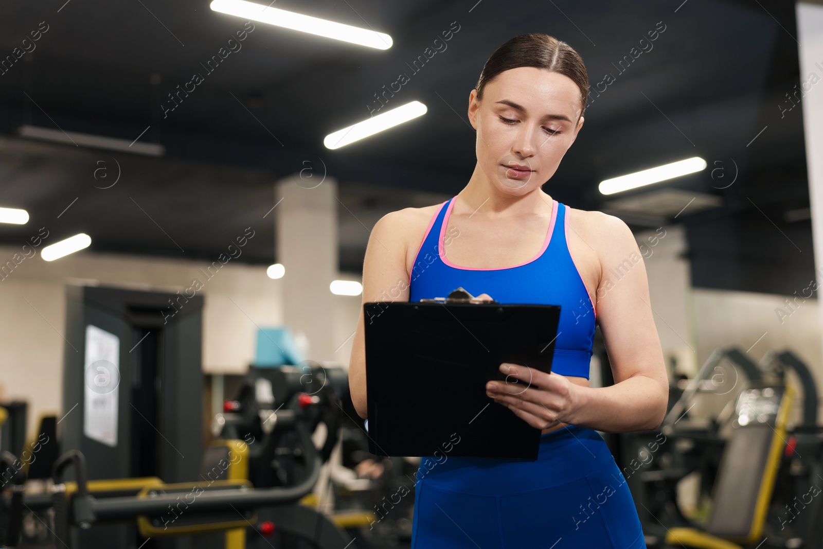 Professional personal trainer with clipboard in gym. Space for text Photo of Professional personal trainer with clipboard in gym. Space for text
