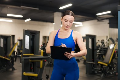 Photo of Professional personal trainer with clipboard in gym