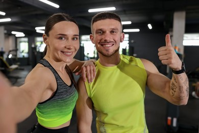 Photo of Happy personal trainers taking selfie in gym