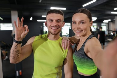 Photo of Happy personal trainers taking selfie in gym