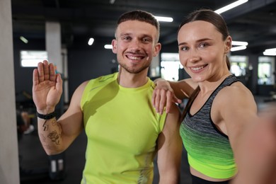 Photo of Happy personal trainers taking selfie in gym