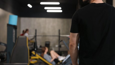 Photo of Professional personal trainer in sport center, back view. Space for text