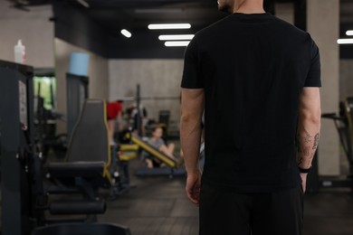 Photo of Professional personal trainer in sport center, back view. Space for text
