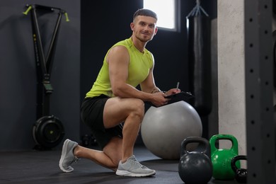 Photo of Personal trainer with clipboard and sports equipment in gym
