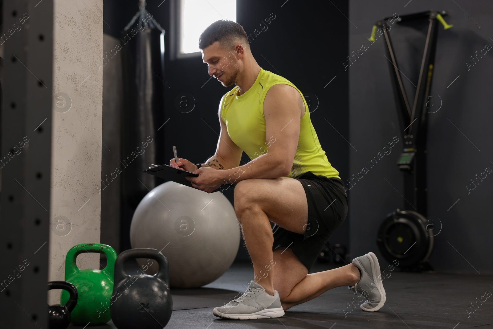 Personal trainer with clipboard and sports equipment in gym Photo of Personal trainer with clipboard and sports equipment in gym