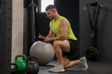 Photo of Personal trainer with clipboard and sports equipment in gym