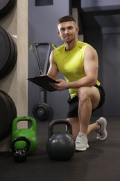 Photo of Personal trainer with clipboard and sports equipment in gym