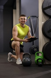 Photo of Personal trainer with clipboard and sports equipment in gym