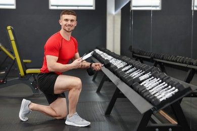Photo of Personal trainer with clipboard and dumbbells in gym