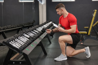 Photo of Personal trainer with clipboard and dumbbells in gym