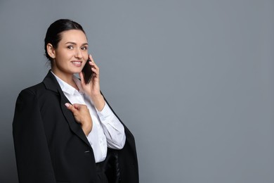 Photo of Confident business woman in suit talking on phone against grey background. Space for text