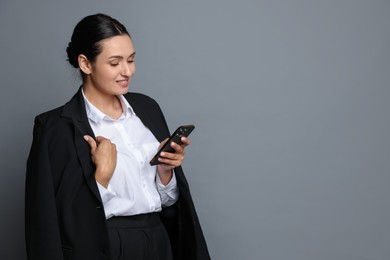 Photo of Confident business woman in suit with smartphone on grey background. Space for text