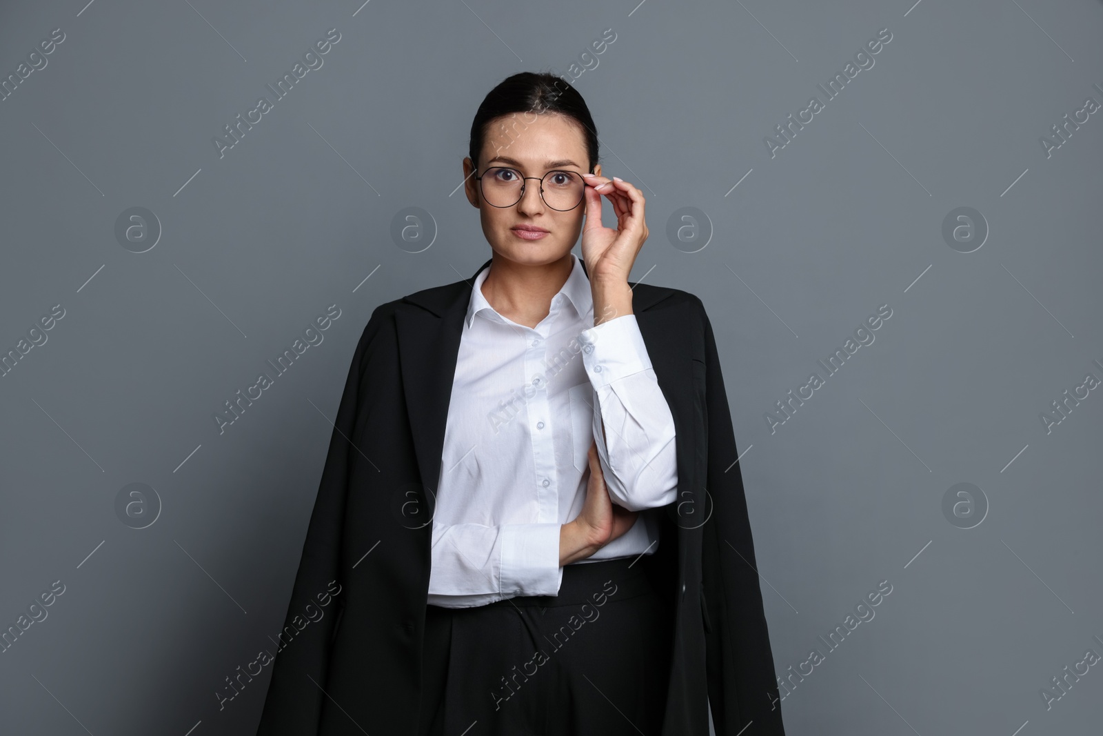 Confident business woman in suit on grey background Photo of Confident business woman in suit on grey background