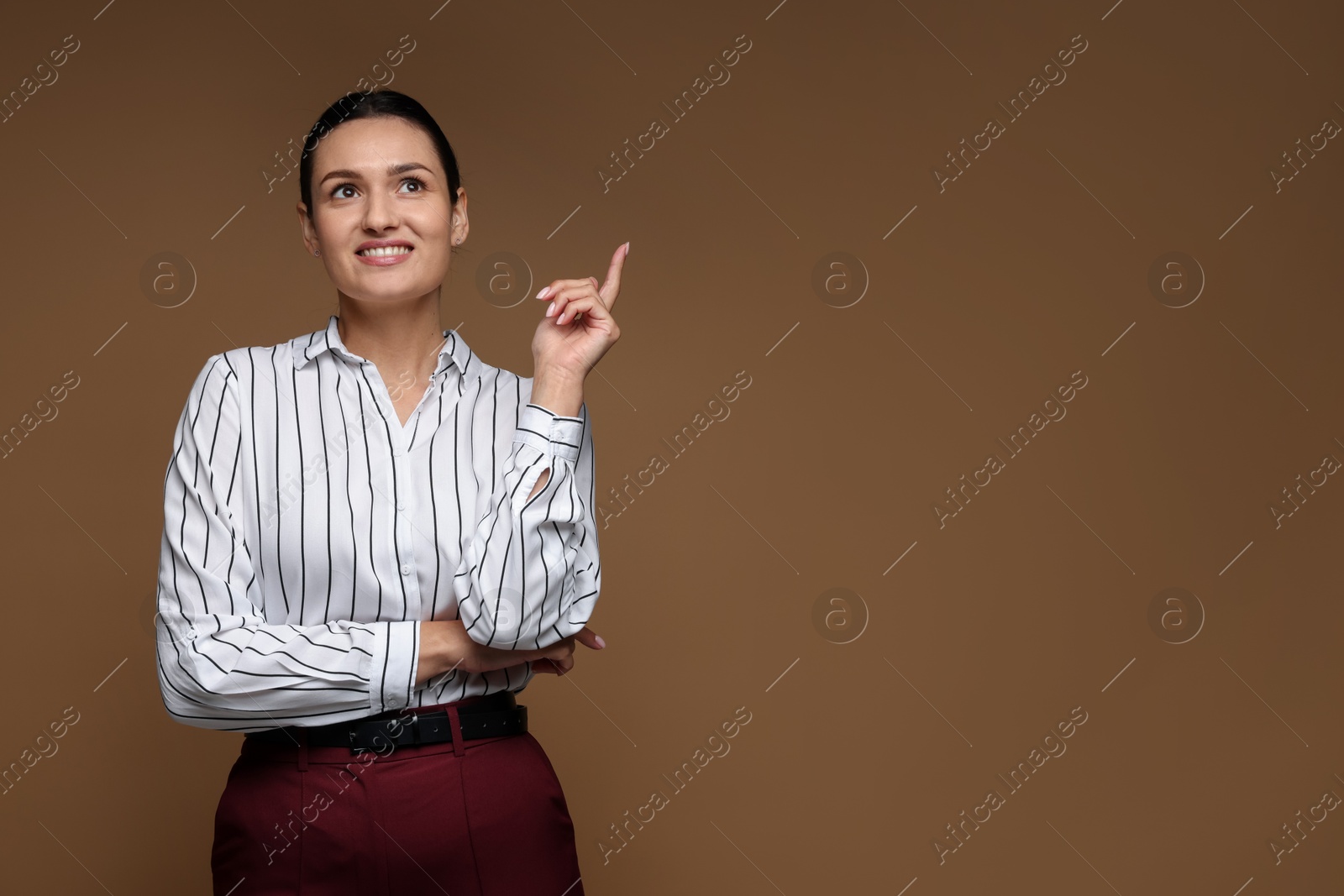Photo of Confident business woman pointing at something on brown background. Space for text