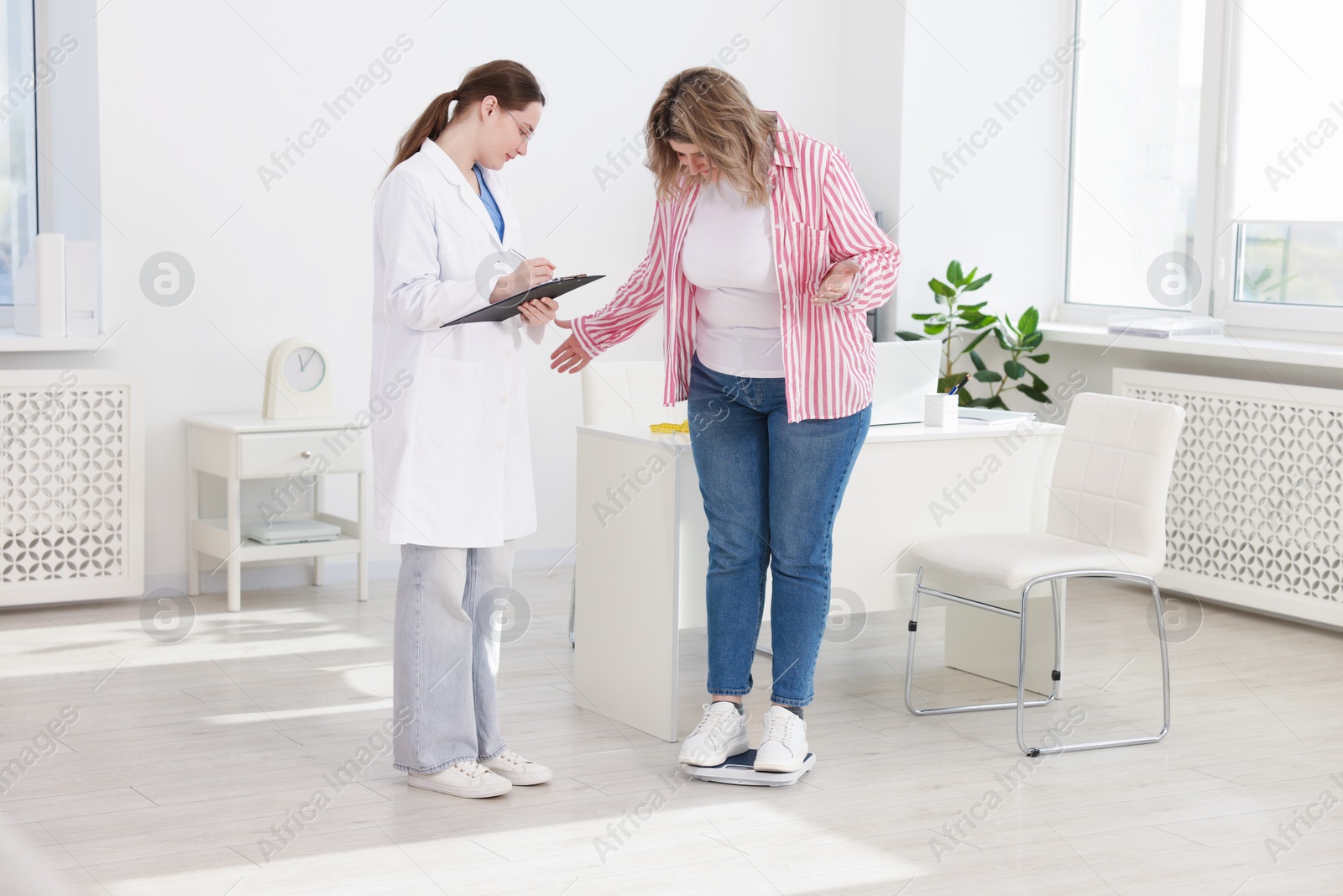 Weight loss. Overweight woman standing on scales during consultation with nutritionist in clinic Photo of Weight loss. Overweight woman standing on scales during consultation with nutritionist in clinic
