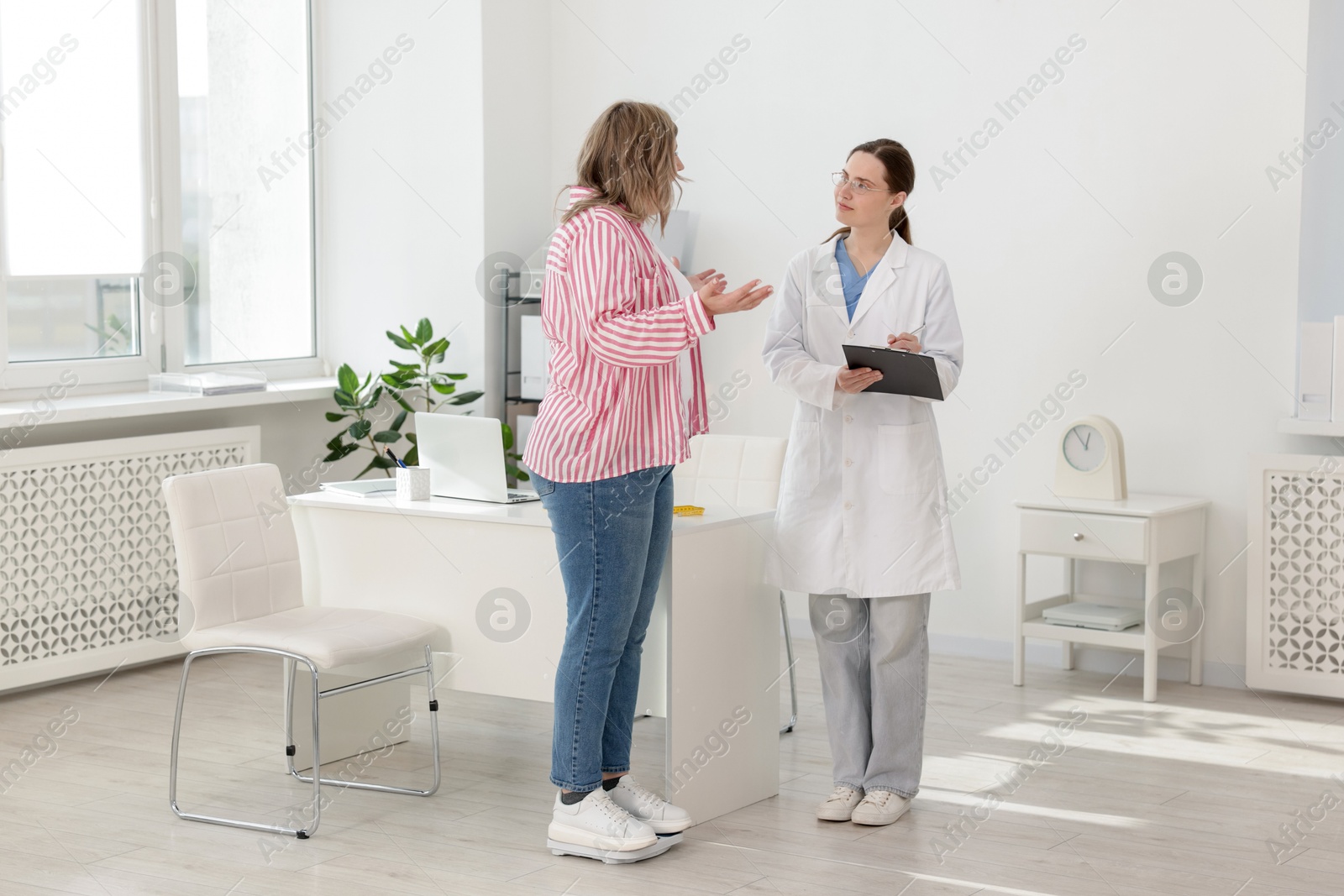 Weight loss. Overweight woman standing on scales during consultation with nutritionist in clinic Photo of Weight loss. Overweight woman standing on scales during consultation with nutritionist in clinic
