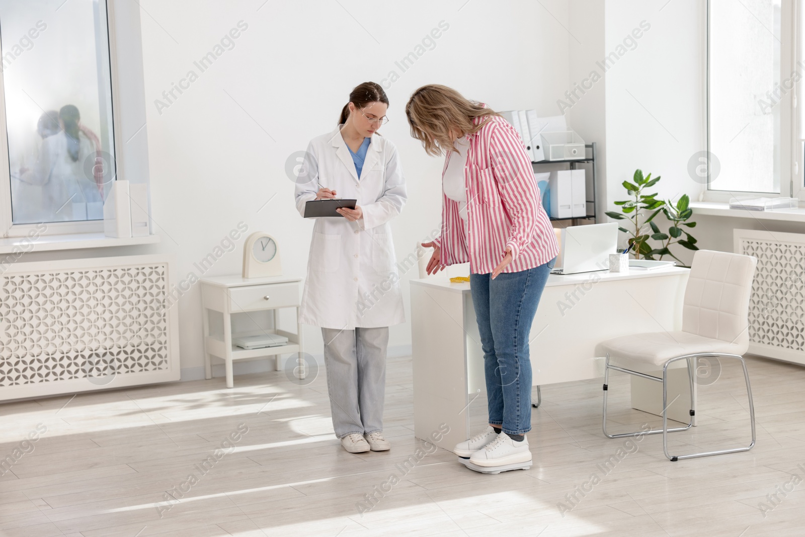 Weight loss. Overweight woman standing on scales during consultation with nutritionist in clinic Photo of Weight loss. Overweight woman standing on scales during consultation with nutritionist in clinic