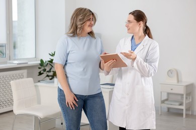 Photo of Weight loss. Nutritionist consulting overweight woman in clinic