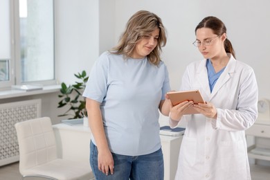 Photo of Weight loss. Nutritionist consulting overweight woman in clinic