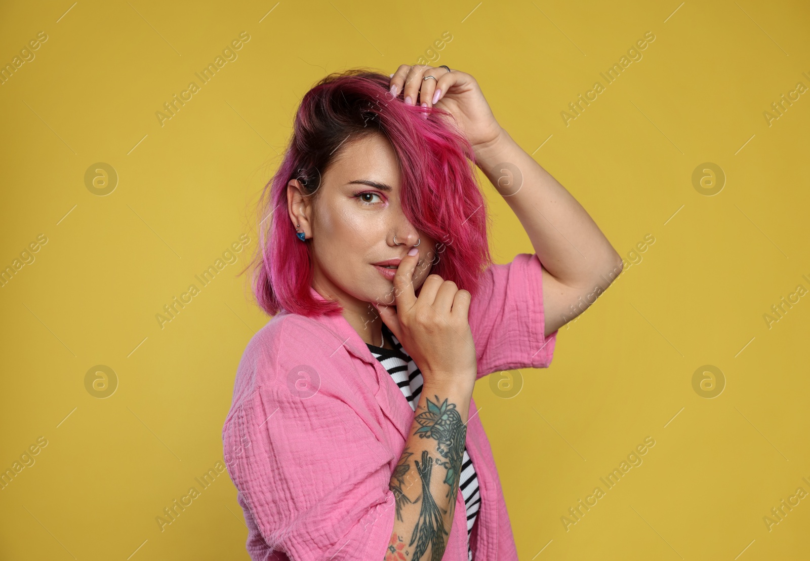 Beautiful woman with pink dyed hair on yellow background Photo of Beautiful woman with pink dyed hair on yellow background