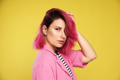 Photo of Beautiful woman with pink dyed hair on yellow background