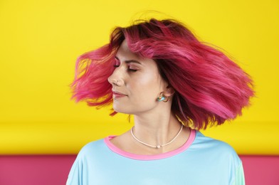 Photo of Beautiful woman with pink dyed hair shaking head on color background
