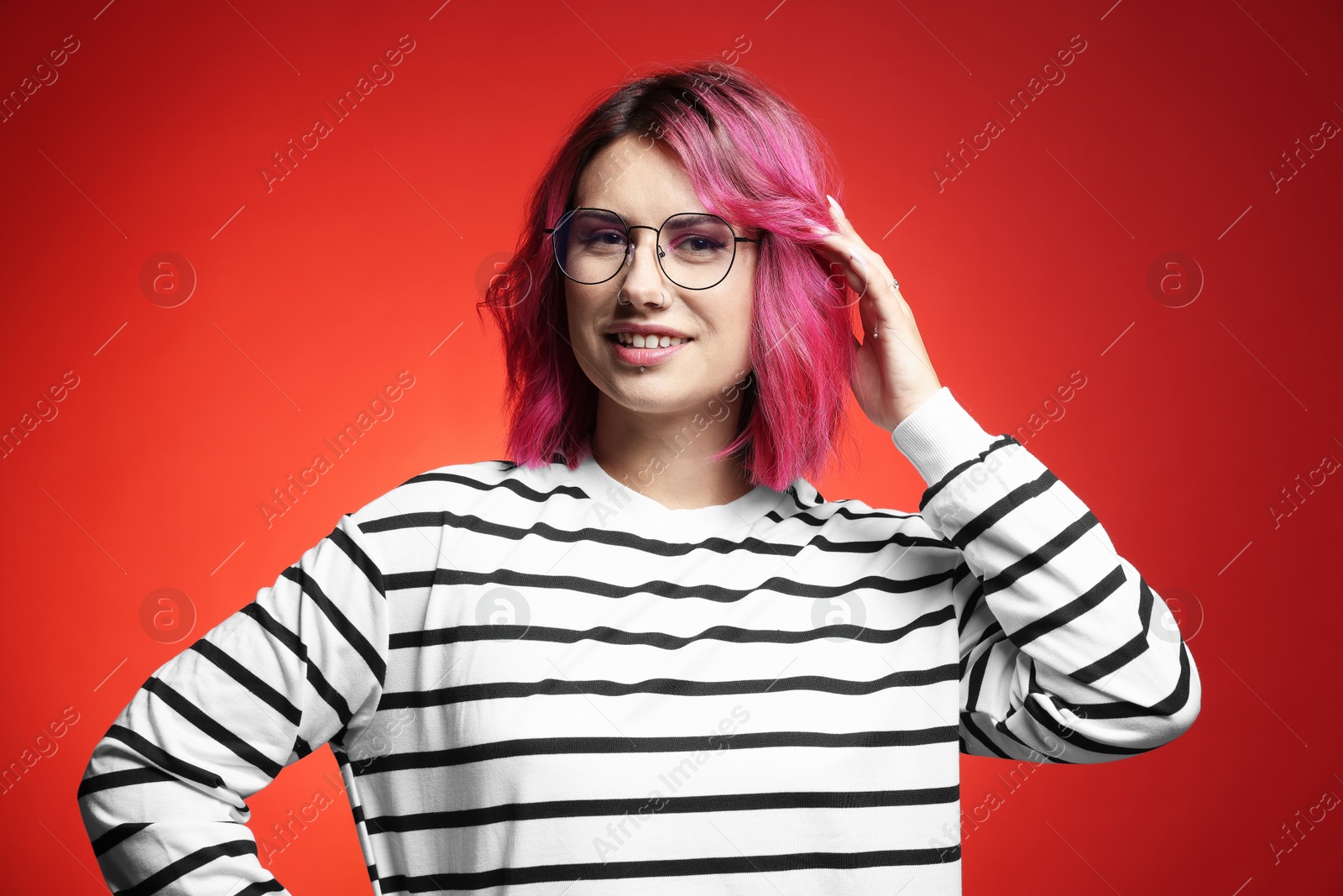 Beautiful woman with pink dyed hair in glasses on red gradient background Photo of Beautiful woman with pink dyed hair in glasses on red gradient background