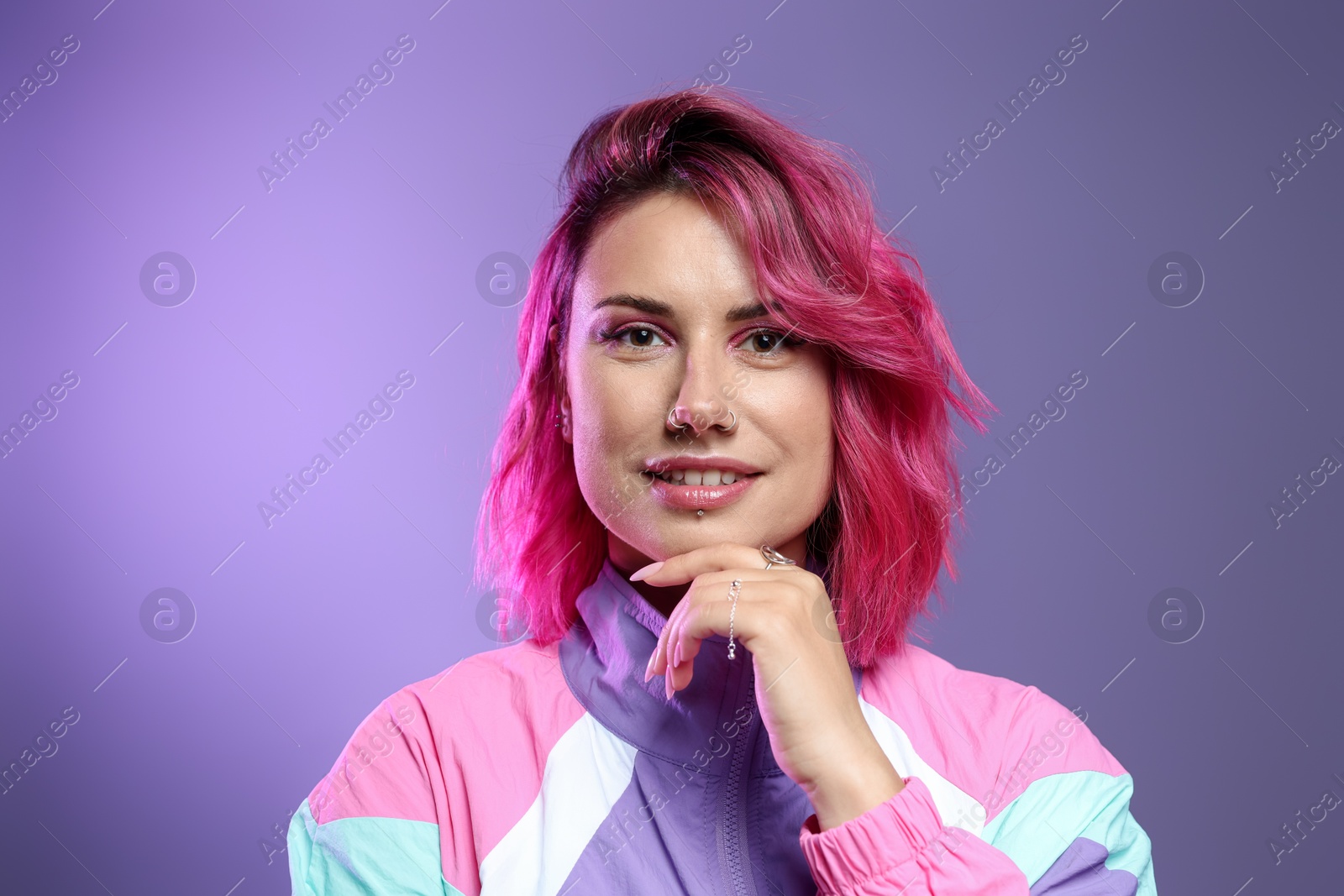 Photo of Beautiful woman with pink dyed hair on violet gradient background