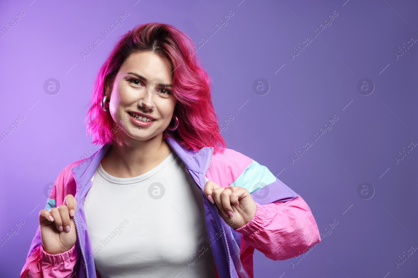 Beautiful woman with pink dyed hair on violet background, space for text Photo of Beautiful woman with pink dyed hair on violet background, space for text