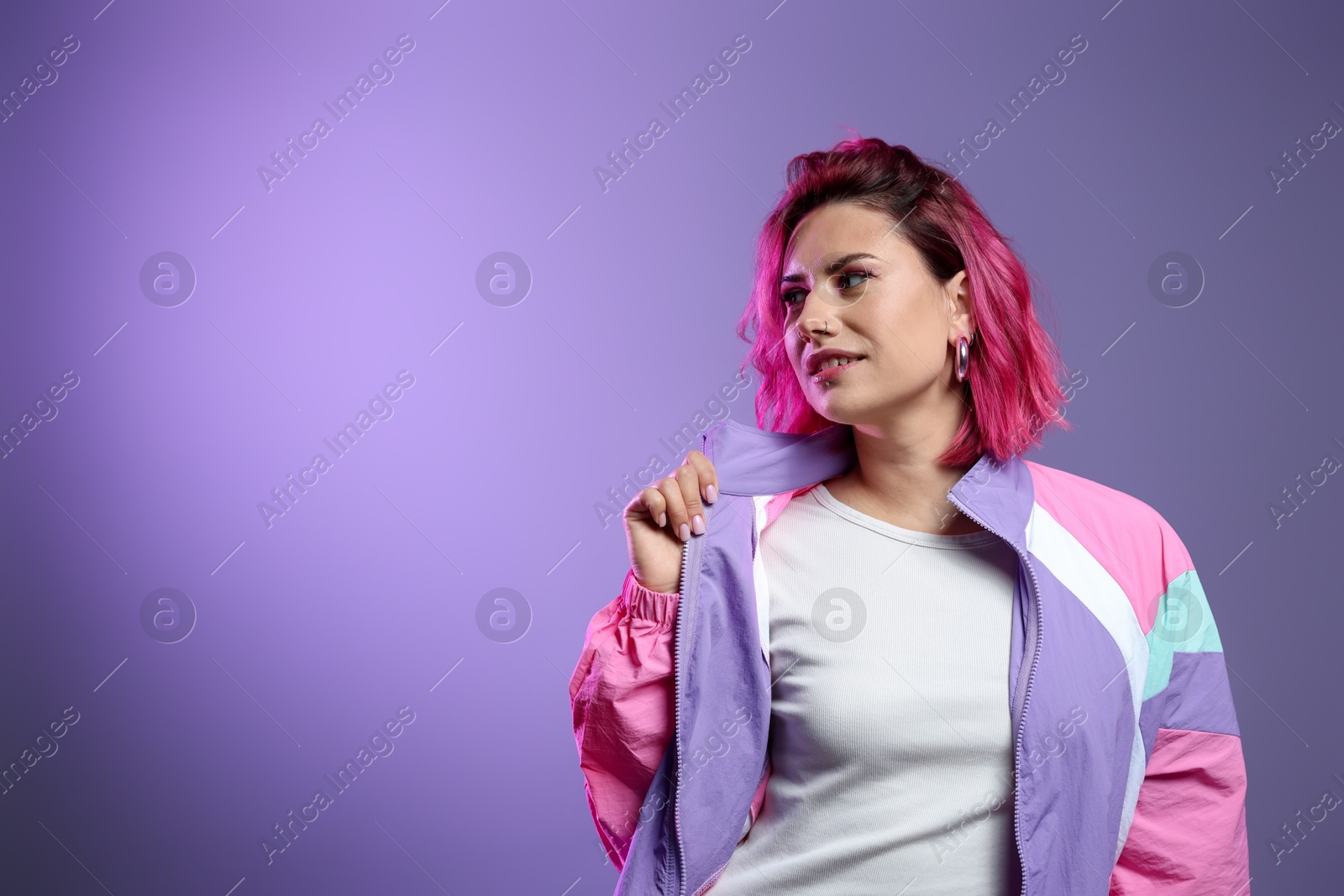 Beautiful woman with pink dyed hair on violet background, space for text Photo of Beautiful woman with pink dyed hair on violet background, space for text